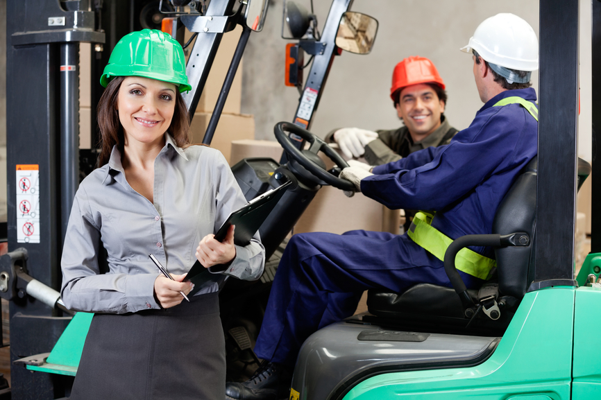 Confident Female Supervisor With Forklift Driver At Warehouse