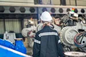 Trabalhador inspeciona máquinas em ambiente industrial.