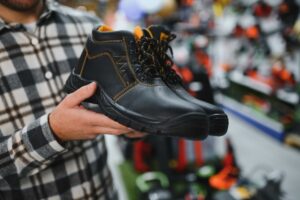 Um homem em uma loja de ferragens escolhe sapatos de segurança para trabalhos de construção.
