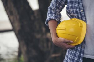 Homem engenheiro segurando capacete de segurança branco para construção civil
