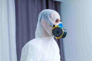 Homem em roupas de proteção e uma máscara de gás em um fundo branco