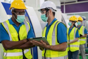 Operários reunidos antes do trabalho e colocando uma máscara.