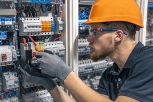 Eletricista trabalhando em um quadro elétrico com fusíveis. Instalação e conexão de equipamentos elétricos. Profissional com ferramentas nas mãos.