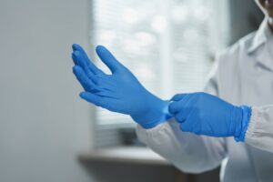 Profissional de saúde colocando cuidadosamente luvas de proteção, garantindo higiene e segurança no ambiente clínico.